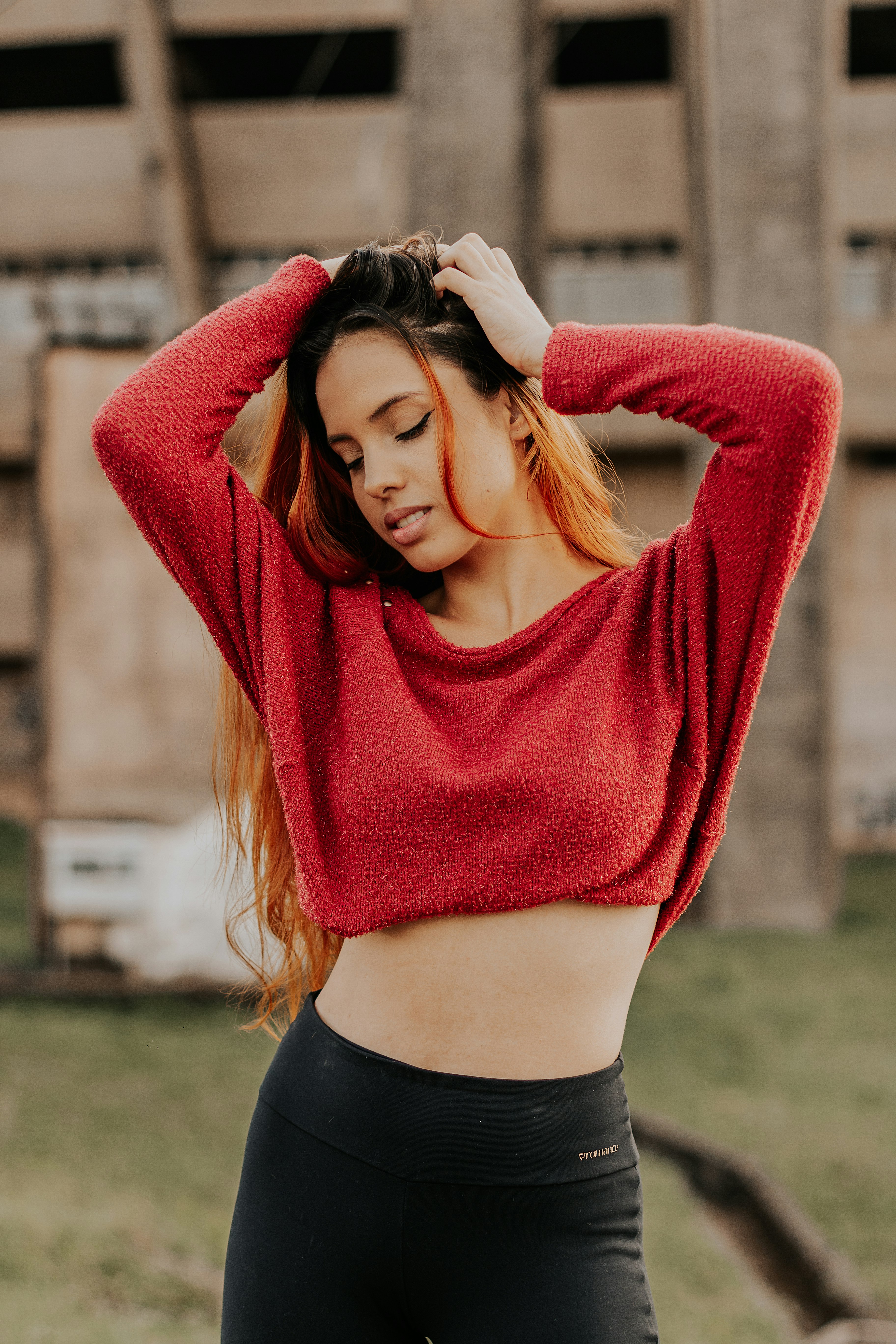 woman in red sweater standing on green grass field during daytime